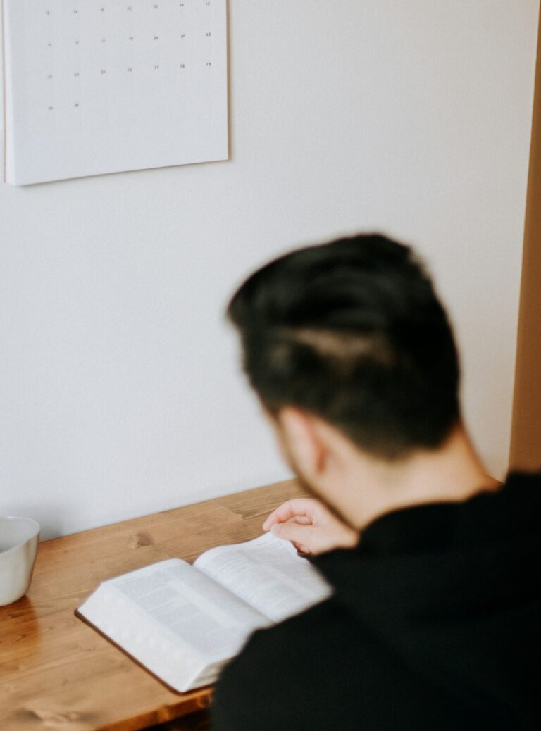 An asian guy is reading a book